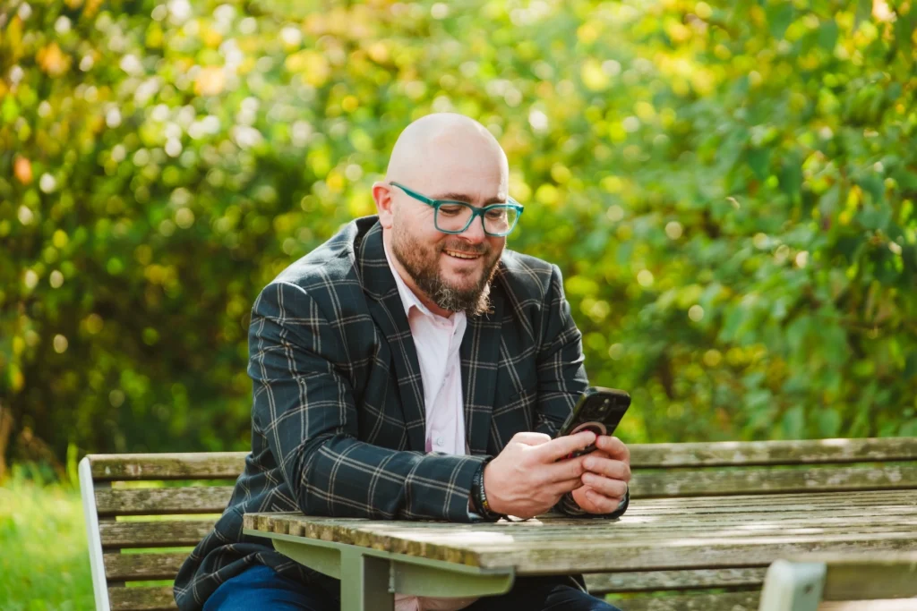 Fuehrungskraefte-Coach Dominik Braun am Smartphone am arbeiten in der Natur